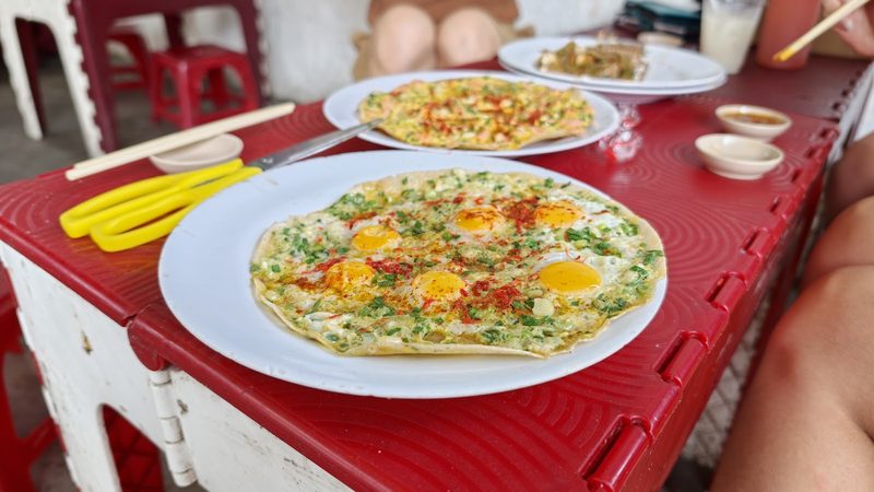 Bánh tráng nướng trên bàn nhựa đỏ vỉa hè